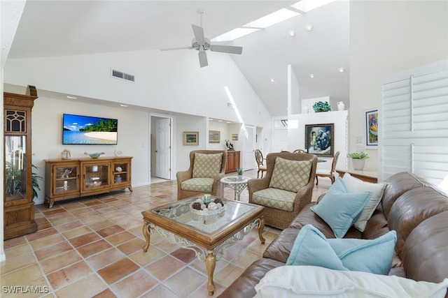 living room with tile patterned flooring, vaulted ceiling with skylight, and ceiling fan