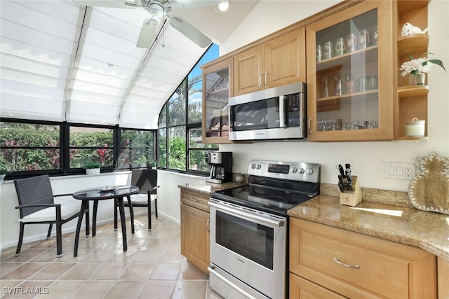 kitchen featuring lofted ceiling, light tile patterned floors, ceiling fan, stainless steel appliances, and light stone countertops