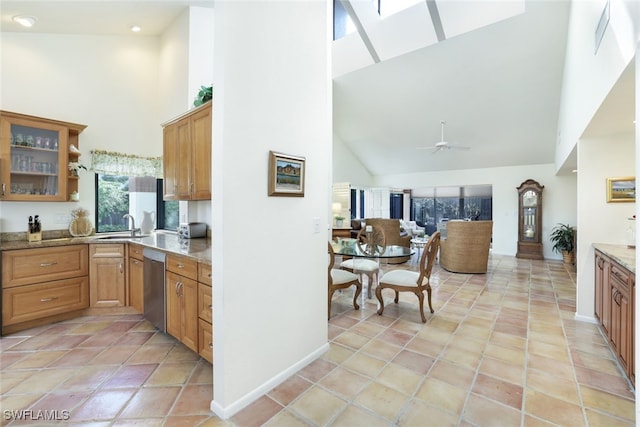 kitchen featuring high vaulted ceiling, dishwasher, sink, ceiling fan, and light stone countertops