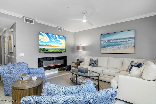 living room featuring ceiling fan, visible vents, a glass covered fireplace, and ornamental molding