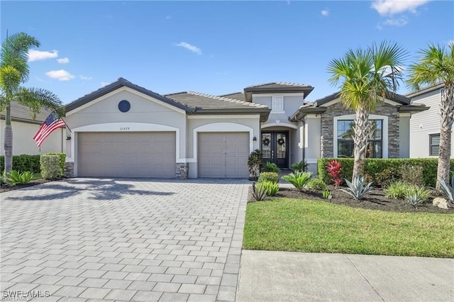 view of front of home featuring a garage, french doors, and a front lawn