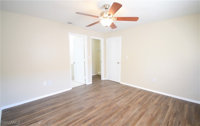 empty room with a ceiling fan, dark wood-style flooring, visible vents, and baseboards