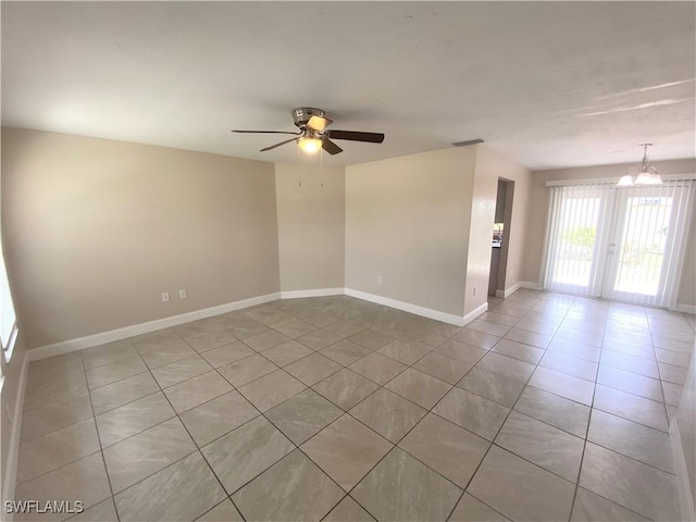 spare room featuring ceiling fan with notable chandelier, light tile patterned flooring, visible vents, and baseboards