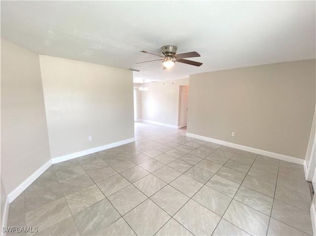 spare room featuring light tile patterned floors, ceiling fan, and baseboards