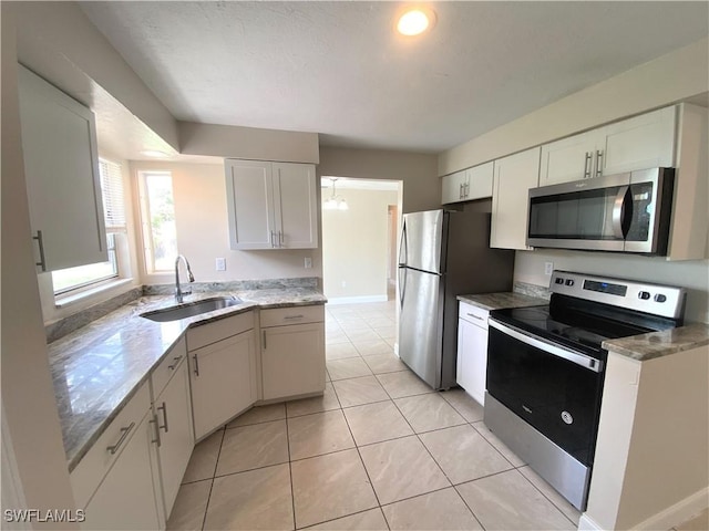 kitchen with light tile patterned flooring, stainless steel appliances, a sink, baseboards, and white cabinets