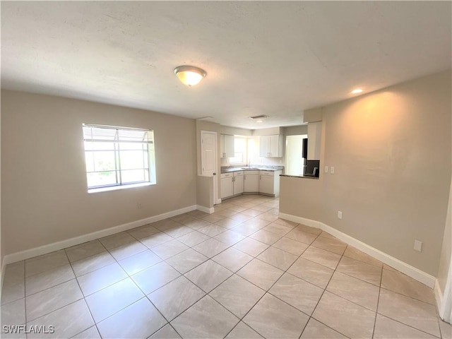 spare room with baseboards and light tile patterned floors