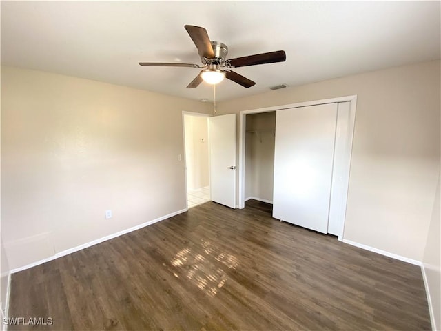 unfurnished bedroom featuring dark wood-type flooring, a closet, a ceiling fan, and baseboards