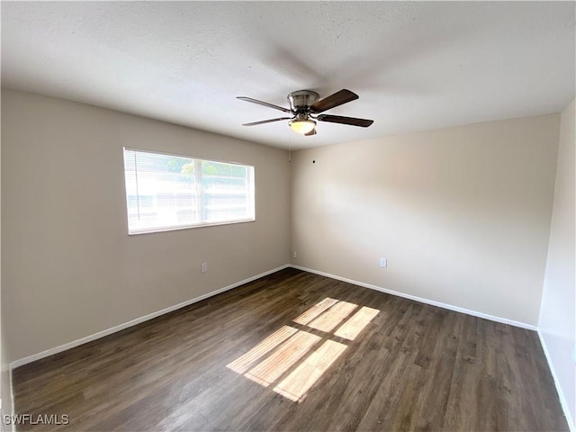 empty room with a ceiling fan, dark wood-style flooring, and baseboards