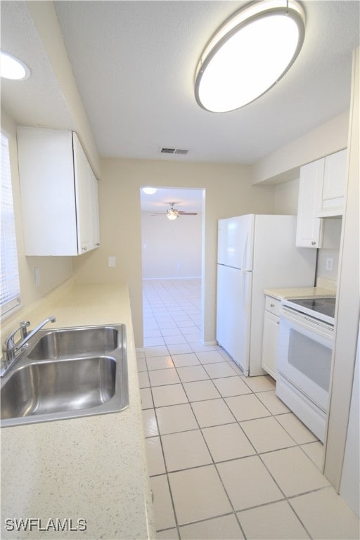 kitchen featuring light countertops, visible vents, white cabinetry, a sink, and white appliances