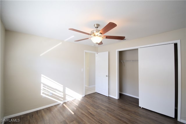 unfurnished bedroom featuring ceiling fan, a closet, baseboards, and dark wood-style flooring