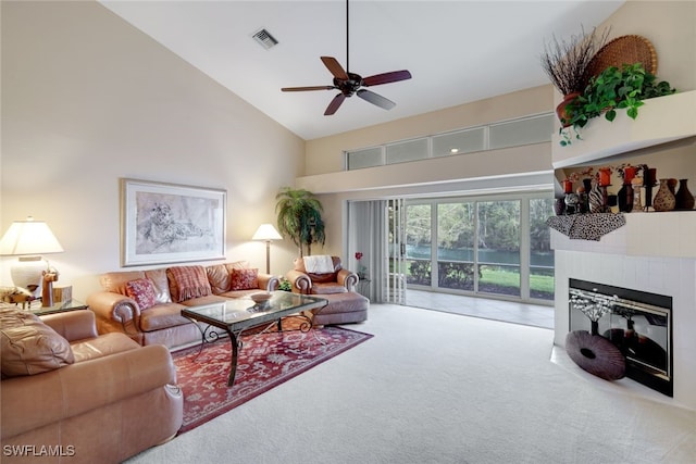 carpeted living room with ceiling fan, a fireplace, and high vaulted ceiling