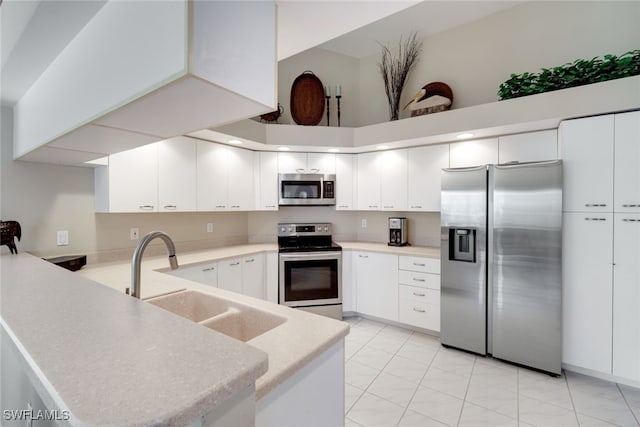 kitchen featuring sink, appliances with stainless steel finishes, a towering ceiling, white cabinets, and kitchen peninsula