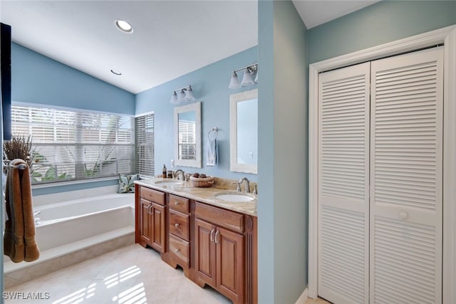 bathroom featuring vaulted ceiling, vanity, tile patterned flooring, and tiled tub