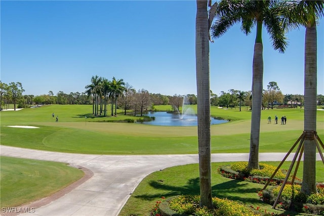 surrounding community with a water view and a lawn