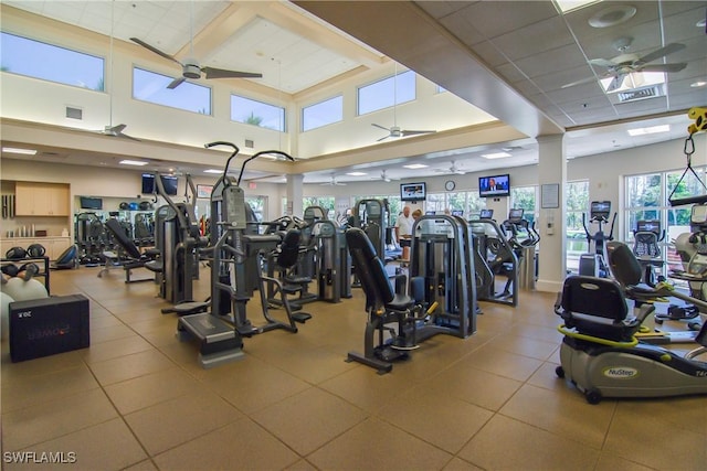 exercise room featuring ceiling fan, a towering ceiling, and a drop ceiling