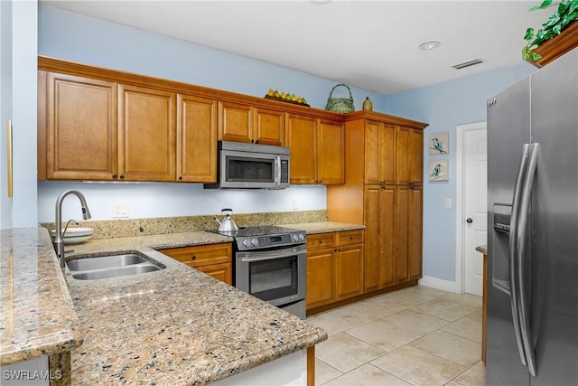 kitchen with sink, stainless steel appliances, light stone countertops, and light tile patterned flooring