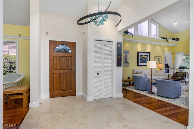 tiled foyer with ceiling fan, a healthy amount of sunlight, and high vaulted ceiling