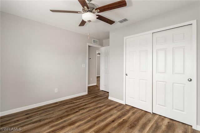 unfurnished bedroom with dark wood-style floors, a closet, visible vents, and baseboards