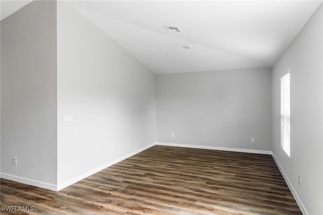 unfurnished room with dark wood-type flooring, visible vents, and baseboards