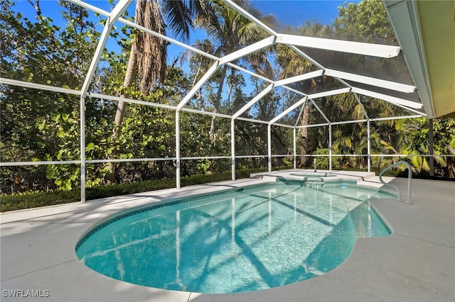 view of swimming pool with glass enclosure, a patio, and a pool with connected hot tub