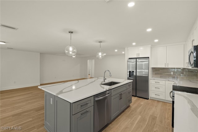 kitchen with stainless steel appliances, gray cabinets, a sink, and white cabinets