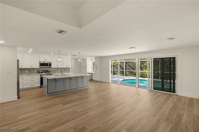 kitchen with open floor plan, appliances with stainless steel finishes, visible vents, and white cabinets