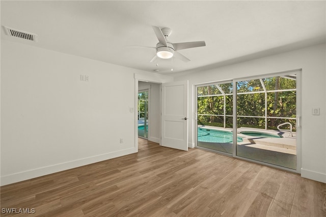 unfurnished room with a ceiling fan, visible vents, baseboards, and wood finished floors