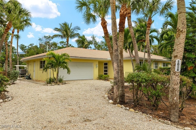 single story home featuring gravel driveway, a garage, and stucco siding