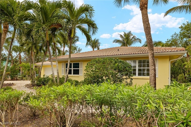 exterior space featuring an attached garage, a tile roof, and stucco siding