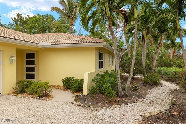 view of side of property with a tile roof and stucco siding