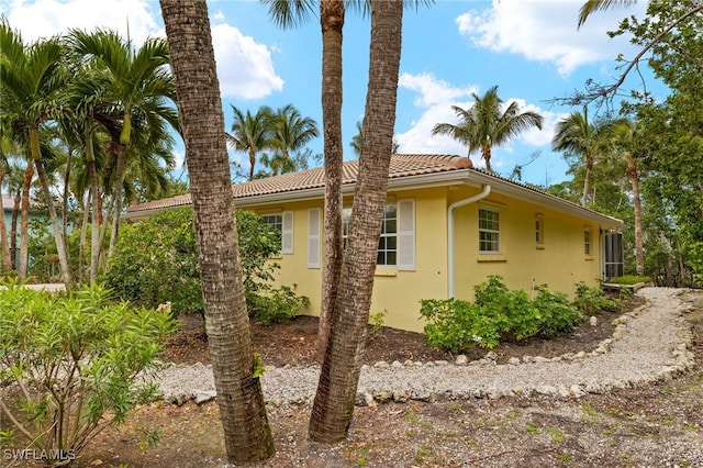 view of side of home featuring a tile roof and stucco siding