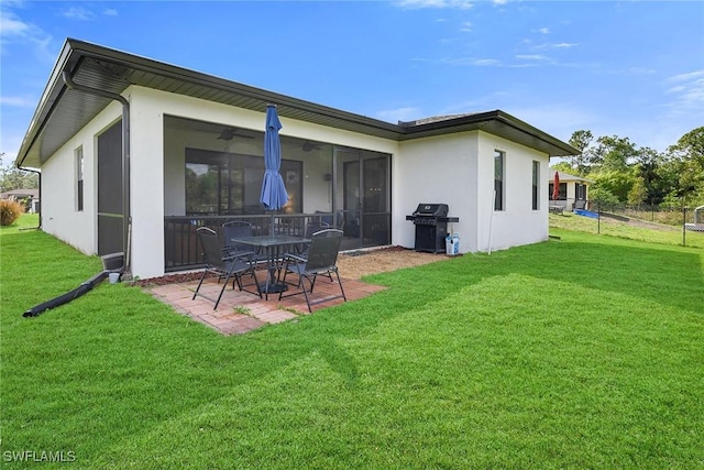 rear view of property with a yard, a patio area, a sunroom, and ceiling fan