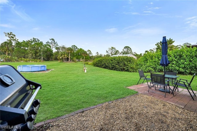 view of community with a yard, a swimming pool, and a patio area