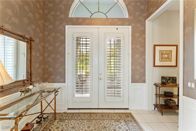 entryway with french doors, a wainscoted wall, and wallpapered walls