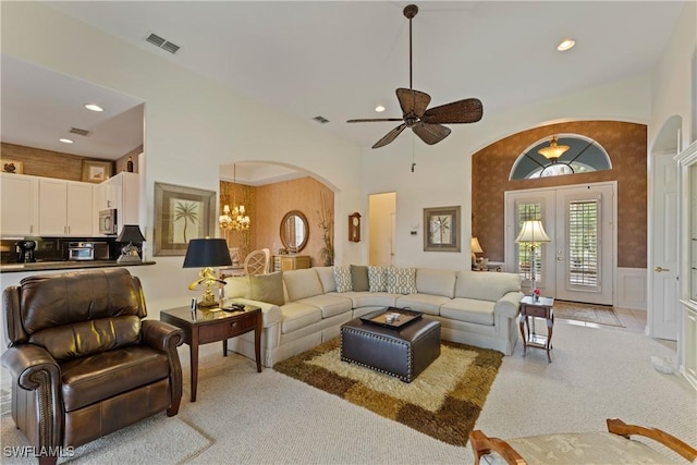 living area with arched walkways, visible vents, an inviting chandelier, wainscoting, and light carpet