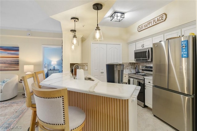 kitchen with a breakfast bar area, a peninsula, white cabinetry, hanging light fixtures, and appliances with stainless steel finishes