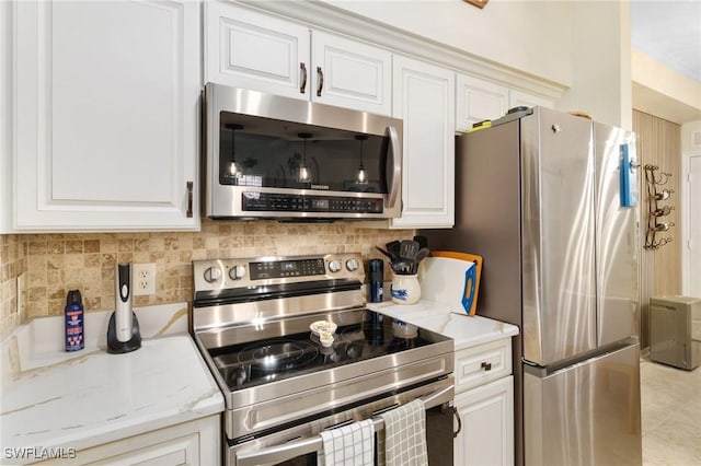 kitchen featuring appliances with stainless steel finishes, light stone counters, and white cabinetry