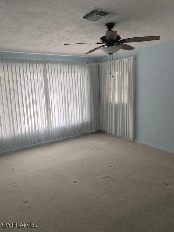 carpeted empty room featuring a textured ceiling and visible vents