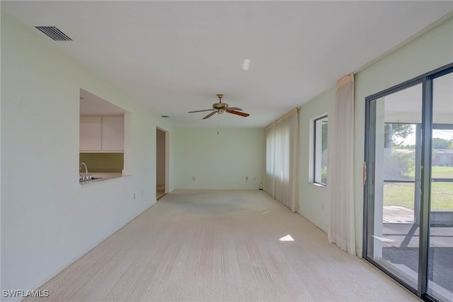 unfurnished room featuring a sink, visible vents, a ceiling fan, and light carpet