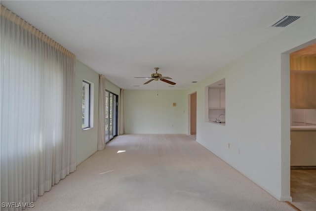 empty room with ceiling fan, visible vents, light carpet, and a sink