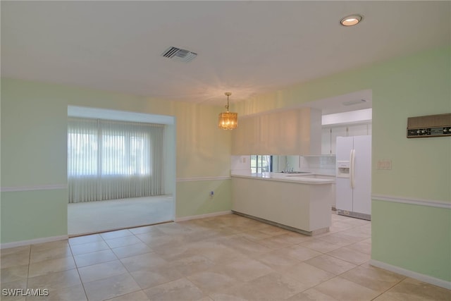 kitchen featuring light countertops, hanging light fixtures, visible vents, a peninsula, and white fridge with ice dispenser