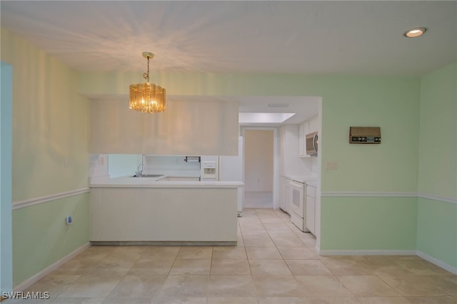 kitchen featuring a sink, stainless steel microwave, light countertops, white electric stove, and a peninsula