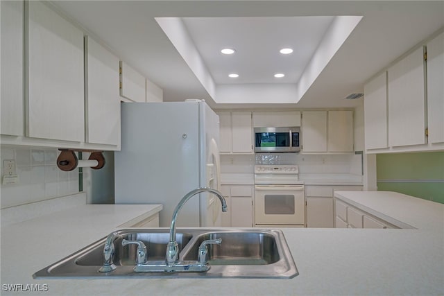 kitchen with light countertops, white cabinetry, and white appliances