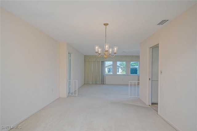 spare room featuring a chandelier, light colored carpet, and visible vents