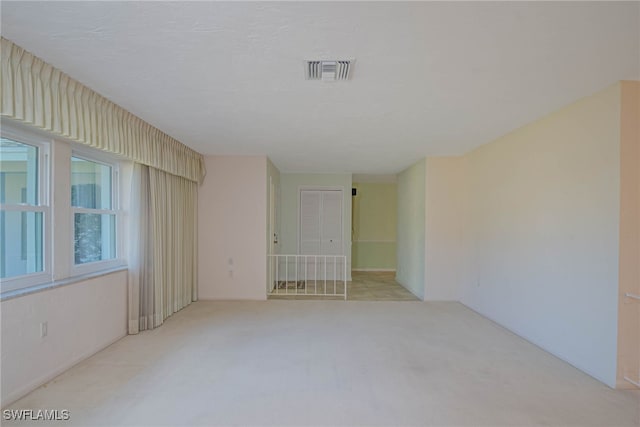 unfurnished room featuring visible vents, light carpet, and a textured ceiling