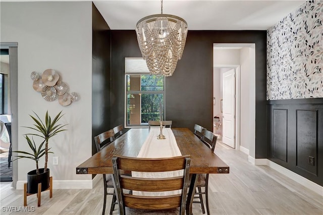 dining room with light wood-type flooring, an inviting chandelier, and baseboards