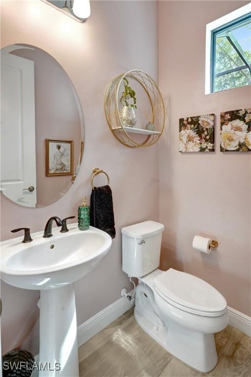 bathroom featuring a sink, wood finished floors, toilet, and baseboards