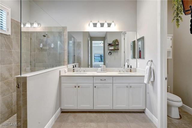 bathroom featuring toilet, a sink, tile patterned floors, double vanity, and walk in shower