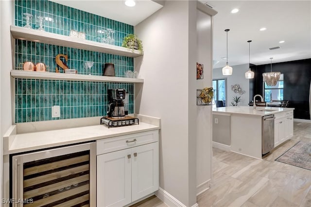 bar with beverage cooler, a sink, stainless steel dishwasher, decorative backsplash, and decorative light fixtures