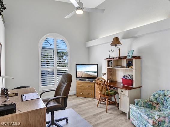 office space featuring ceiling fan, light hardwood / wood-style flooring, and a towering ceiling